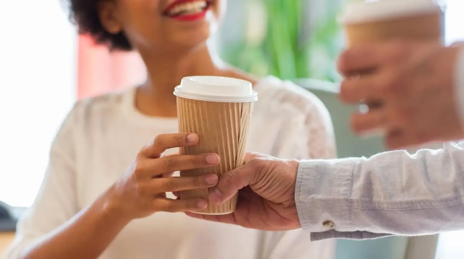 One person handing another a warm cup of coffee